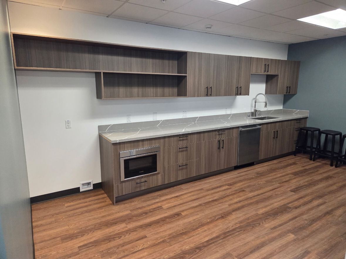 Finished office break room with custom cabinetry, quartz counter and luxury vinyl plank flooring
